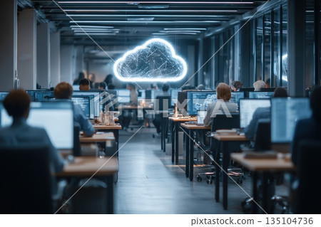 Employees work in a modern office focusing on cloud computing and data analysis with multiple laptops in use 135104736