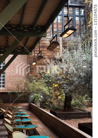 Outdoor cafe with infrared heaters suspended from ceiling to comfort visitors during cold season Outdoor cafe with infrared heaters suspended from ceiling to comfort visitors during cold season 135104878