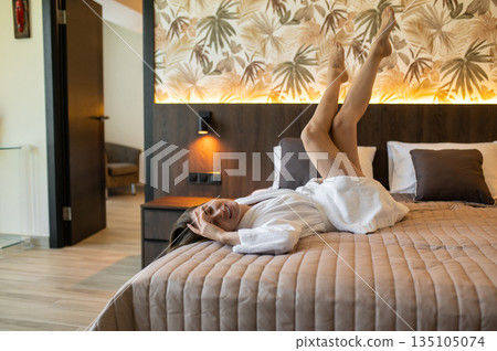 Young woman in bathrobe lying on the bed and feeling relaxed 135105074