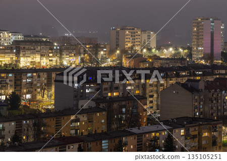 Night panorama of Pristina, capital city of Kosovo, capturing residential architecture, apartment buildings, warm window lights and winter urban mood 135105251