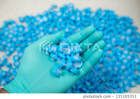 Womans hand in protective glove holding syringe filters used in scientific research. Womans hand in protective glove holding syringe filters used in scientific research. 135105351