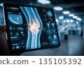 A patient examines a clear X-ray of the knee joint displayed on a tablet screen while in a clinical environment. The scene highlights advanced medical technology. 135105392