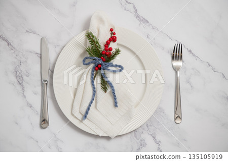 Christmas table setting with white plate, napkin, fir tree branch and red berries decoration 135105919