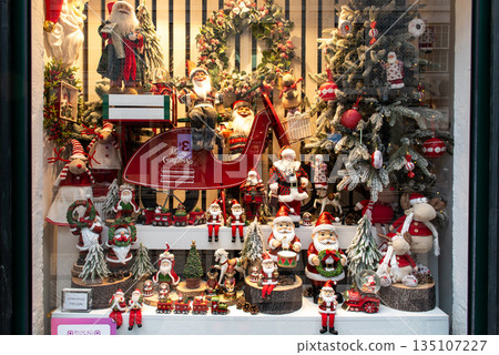 Festive christmas shop window with santa figurines and holiday decorations Festive christmas shop window with santa figurines and holiday decorations 135107227