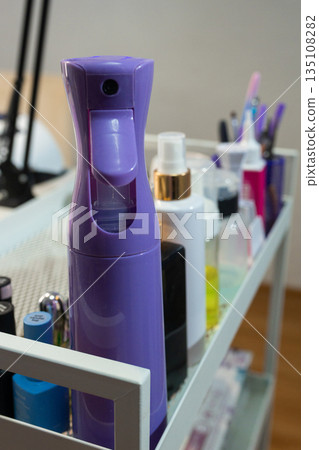 Professional manicure cosmetics and spray bottle on beauty salon trolley. Nail care products organized on workstation. Beauty industry, hygiene and nail service concept. 135108282