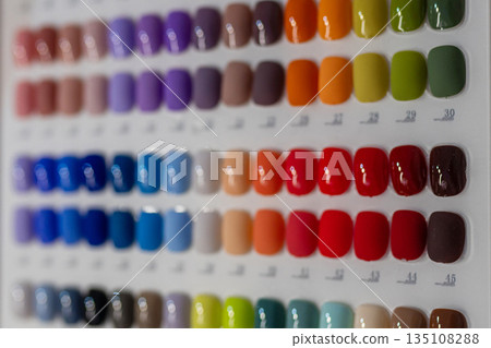 Nail polish color palette samples displayed on manicure table in beauty salon. Variety of gel polish shades for nail design selection. Nail care, fashion and cosmetic industry concept. Nail polish color palette samples displayed on manicure table in beauty salon. Variety of gel polish shades for nail design selection. Nail care, fashion and cosmetic industry concept. 135108288