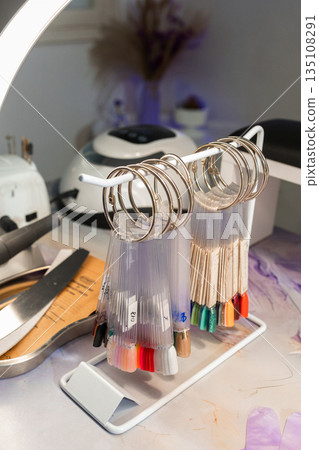 Nail polish color palette samples displayed on manicure table in beauty salon. Variety of gel polish shades for nail design selection. Nail care, fashion and cosmetic industry concept. Nail polish color palette samples displayed on manicure table in beauty salon. Variety of gel polish shades for nail design selection. Nail care, fashion and cosmetic industry concept. 135108291
