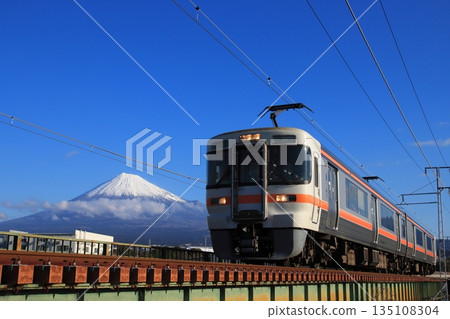 Minobu Line 313 series train crossing a railway bridge watched over by Mount Fuji towering beautifully against the winter sky. Photo taken on January 1, 2026 Minobu Line 313 series train crossing a railway bridge watched over by Mount Fuji towering beautifully against the winter sky. Photo taken on January 1, 2026 135108304
