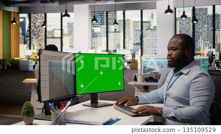 Technician works on wind turbine CAD design using green screen PC, doing renewable energy research. RD specialist does digital modeling of wind energy generator equipment on mockup computer, camera A 135109529