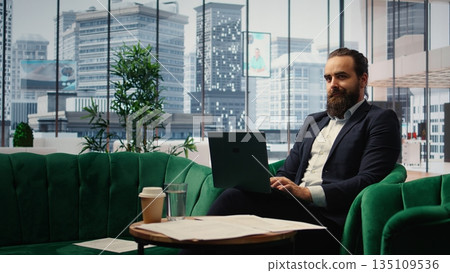 Male leader sitting in a smart office demonstrating authority and productivity, showcasing empowerment while he manages company investments. Chief executive officer in his personal office. Camera A. 135109536