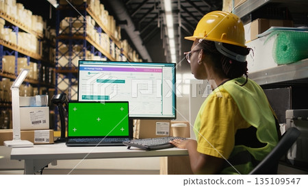 Female warehouse clerk checking awb labels next to chroma key on screen, working in depot with industrial storage racks. Fulfillment center deal with distribution and e-commerce. Camera A. Female warehouse clerk checking awb labels next to chroma key on screen, working in depot with industrial storage racks. Fulfillment center deal with distribution and e-commerce. Camera A. 135109547