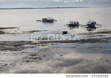 可以看到海面上的雲朵和藍天，退潮後的海面，一艘小船，以及對岸的陸地和天空。 135109568