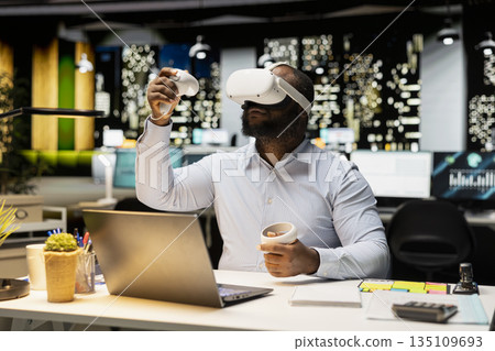 African american employee using AI tools with virtual reality late at night, working hard in the office with VR glasses to ensure fact checking and forecasting projections. Strategy room. 135109693