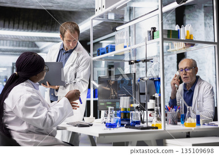Diverse researchers collaborate in lab with molecular analysis tools, experiment highlighting advanced healthcare, biotechnology research and medical discovery through analytical methods. 135109698