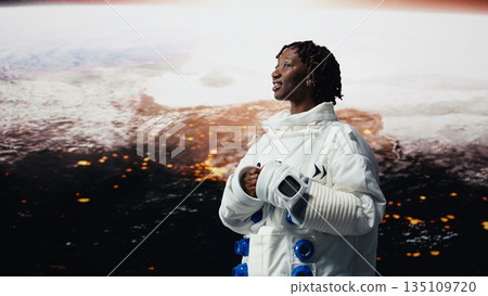 Jolly orbital station astronaut delighted by beauty of planet in space, using AR tech. Cosmonaut using augmented reality looking in awe at galaxy celestial bodies, rotating 360 degrees, camera A 135109720