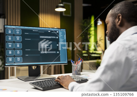 Male PC user interacting with AI chat system on computer at office after hours, highlighting the evolution of artificial intelligence. Chatbot services and digital tools for productivity. 135109766
