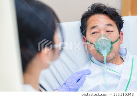 A male hospitalized patient talking while wearing a ventilator A male hospitalized patient talking while wearing a ventilator 135110348