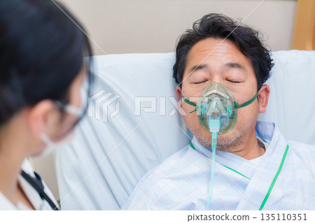 一名男性住院病人戴著呼吸器說話 一名男性住院病人戴著呼吸器說話 135110351