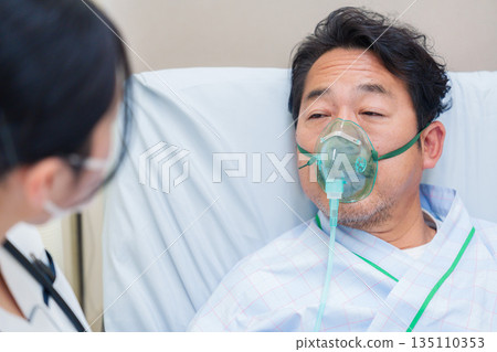 一名男性住院病人戴著呼吸器說話 一名男性住院病人戴著呼吸器說話 135110353