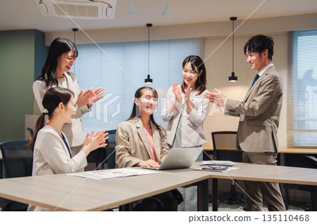 A female employee receives applause from her office colleagues 135110468