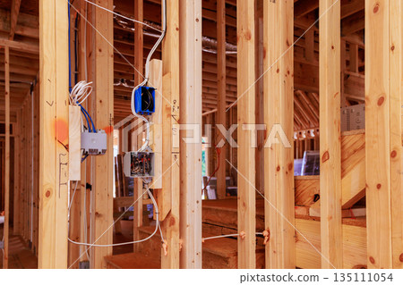 Workers are on installing electrical systems within wooden frames of house being built 135111054