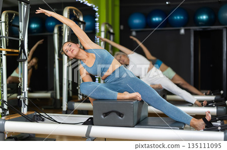 Woman doing bends on a reformer Woman doing bends on a reformer 135111095