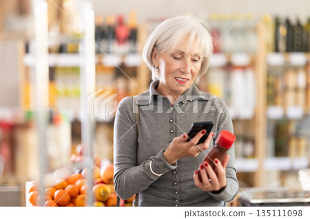 Elderly woman scanning qr code for ketchup 135111098