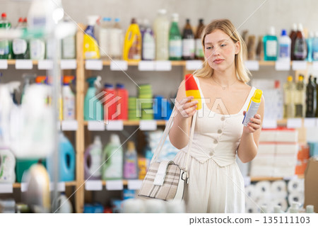 Woman in supermarket choosing insect repellent Woman in supermarket choosing insect repellent 135111103