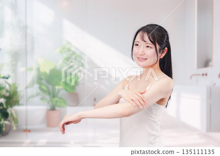 Young woman applying cream to her arms 135111135