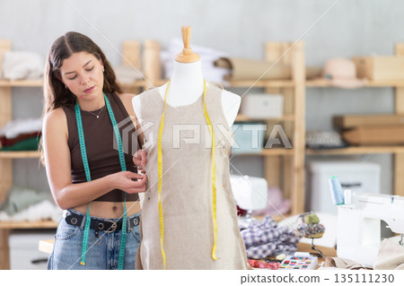 Dressmaker constructing custom dress on mannequin in sewing workshop Dressmaker constructing custom dress on mannequin in sewing workshop 135111230