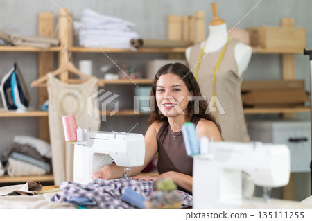 Female fashion designer sewing to order in the workshop 135111255