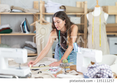 Woman tailor making chalk marks on fabric Woman tailor making chalk marks on fabric 135111257