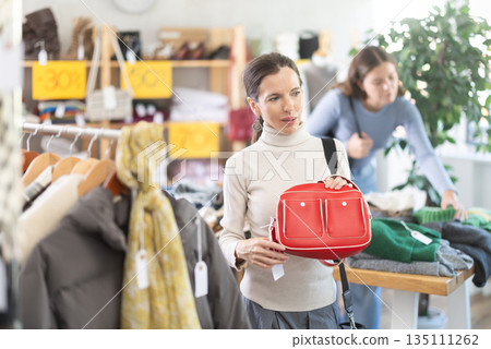 Woman chooses fashionable handbag in clothing boutique 135111262