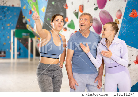 Sports women and man are actively discussing the successes and mistakes of other athletes on mountaineering simulator 135111274