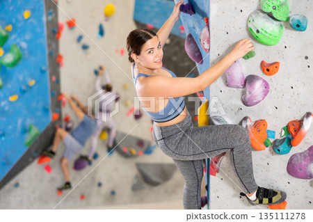 Young woman practicing rock climbing on climbing wall Young woman practicing rock climbing on climbing wall 135111278