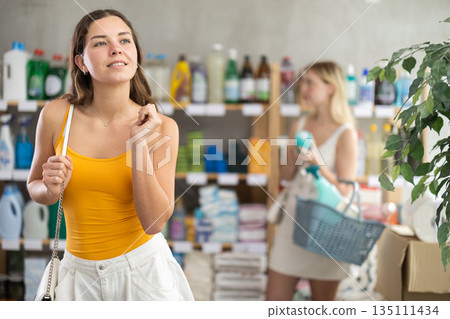 Girl in store and looking for something at shop window, other client shopping in background 135111434
