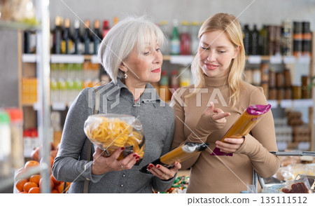 Family shopping at supermarket - choosing spaghetti and pasta in grocery section Family shopping at supermarket - choosing spaghetti and pasta in grocery section 135111512
