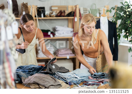 Two young women choosing trousers in store Two young women choosing trousers in store 135111525
