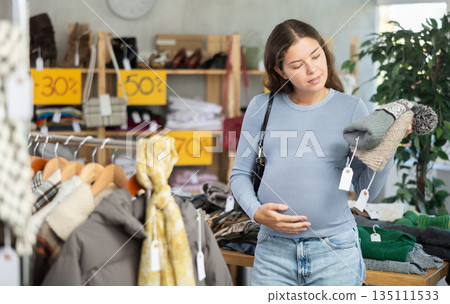 Pregnant woman choosing hat in clothing store 135111533
