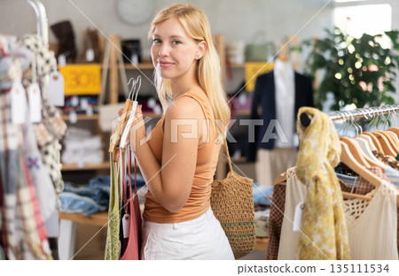 Young woman choosing lazy clothes at discounts Young woman choosing lazy clothes at discounts 135111534