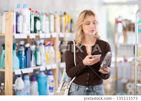 Before making purchase, girl buyer scan QR code on packaging of room spray aerosol 135111573