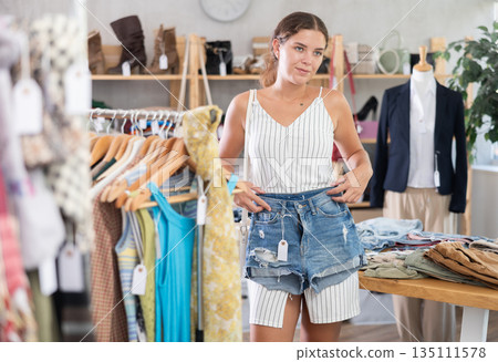 Young woman choosing denim shorts 135111578