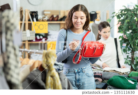 Young woman choosing handbag in clothing store Young woman choosing handbag in clothing store 135111630