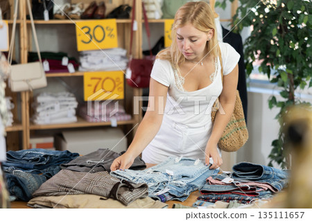 Young woman choosing jeans in clothing store Young woman choosing jeans in clothing store 135111657