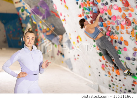 Portrait of slender athletic woman climber on background of climbing wall Portrait of slender athletic woman climber on background of climbing wall 135111663