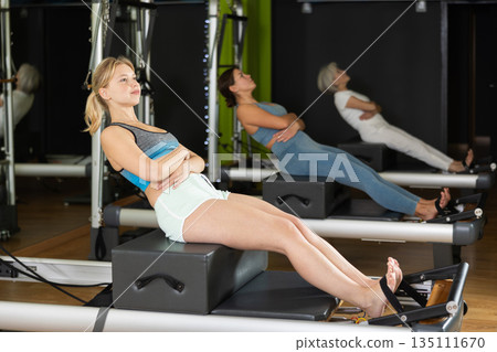 Woman doing bends on a reformer Woman doing bends on a reformer 135111670