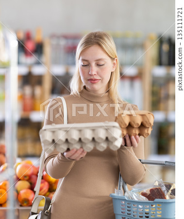 Young woman choosing eggs in grocery store Young woman choosing eggs in grocery store 135111721