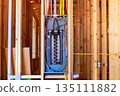 Workers have installed an electrical panel in beams framework of house being built at residential neighborhood. 135111882