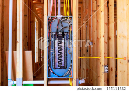 Workers have installed an electrical panel in beams framework of house being built at residential neighborhood. 135111882