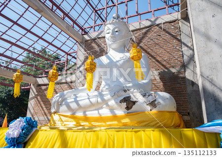 Damaged white Buddha situated in unfinished Viharn in countryside area of Chiang Rai province, Thailand. A Buddha statue is a revered, symbolic sculpture representing the historical Buddha or other en Damaged white Buddha situated in unfinished Viharn in countryside area of Chiang Rai province, Thailand. A Buddha statue is a revered, symbolic sculpture representing the historical Buddha or other en 135112133
